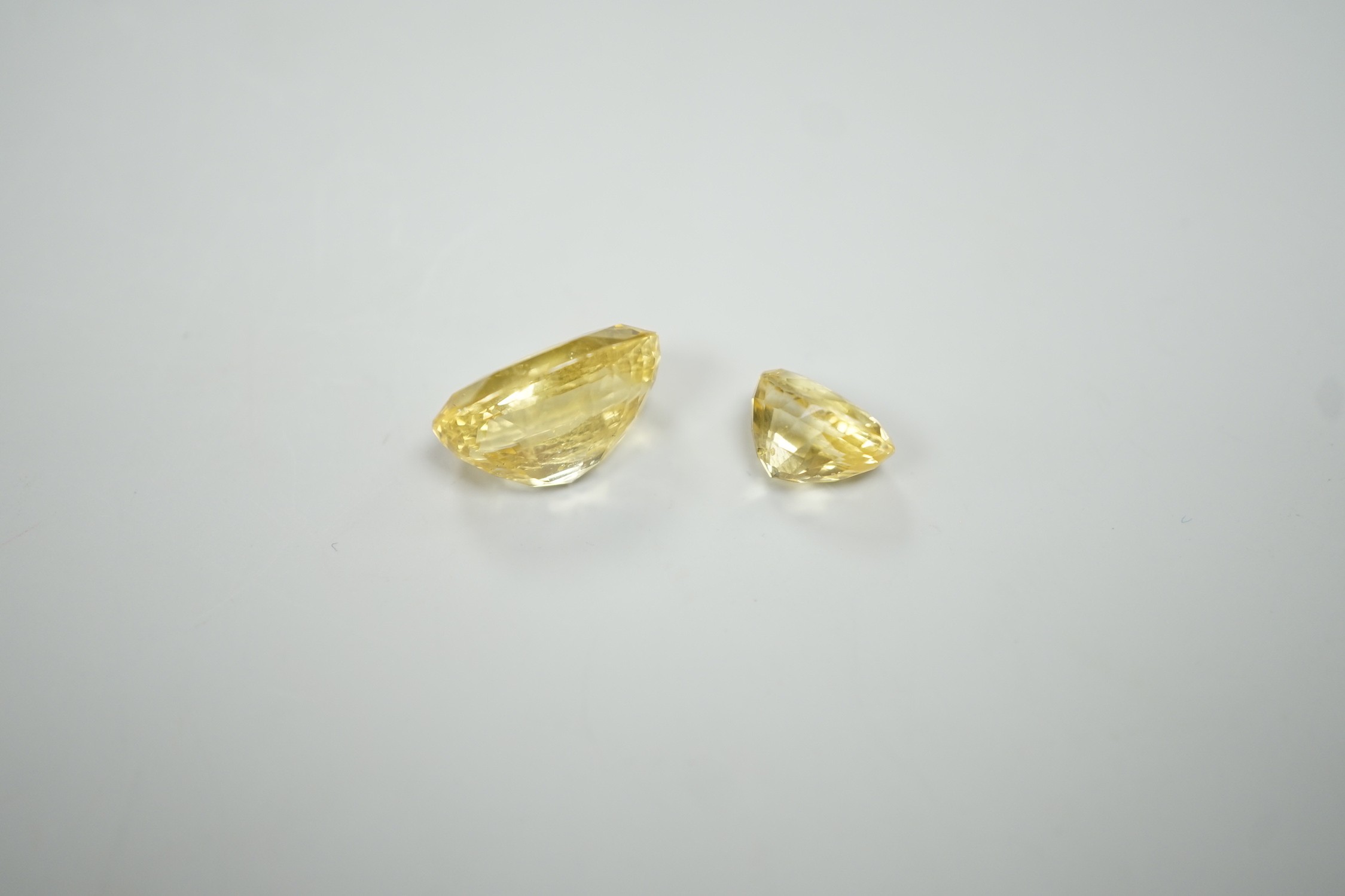 Two oval cut unmounted yellow sapphires, weighing approximately 13.00ct and 4.60ct.